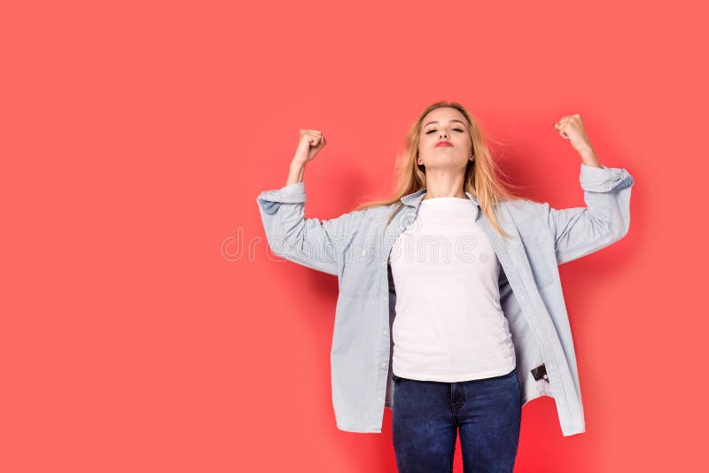 La muchacha rubia joven le muestra fuerza en fondo rojo foto de archivo libre de regalías La muchacha rubia joven le muestra fuerza en fondo rojo foto de archivo libre de regalías