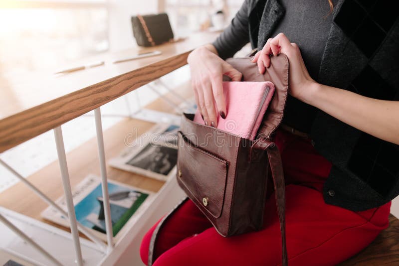 La muchacha saca una libreta de su bolso fotografía de archivo La muchacha saca una libreta de su bolso fotografía de archivo