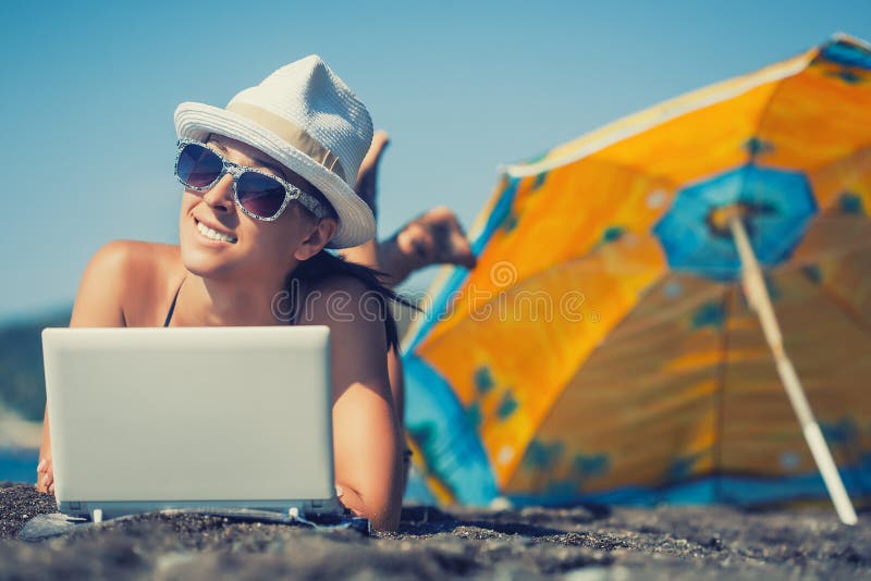 La muchacha sonriente feliz está tomando el sol con el ordenador portátil fotos de archivo libres de regalías La muchacha sonriente feliz está tomando el sol con el ordenador portátil fotos de archivo libres de regalías