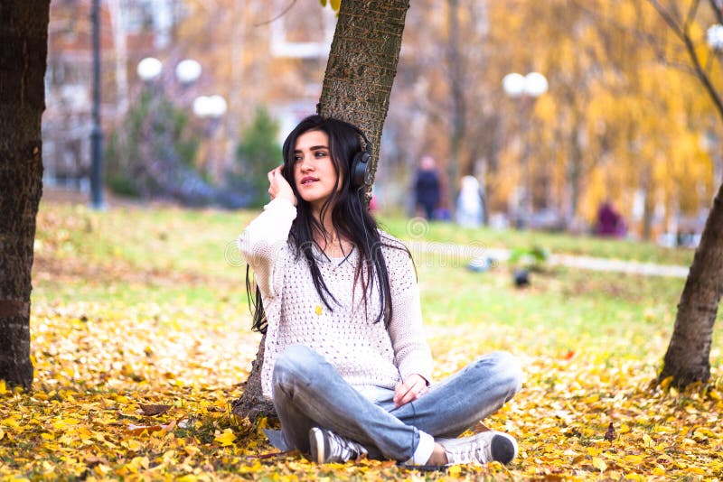 La mujer adolescente feliz que escucha la música y se relaja en parque del otoño Árboles amarillos, tiempo de caída hermoso fotos de archivo libres de regalías La mujer adolescente feliz que escucha la música y se relaja en parque del otoño Árboles amarillos, tiempo de caída hermoso fotos de archivo libres de regalías