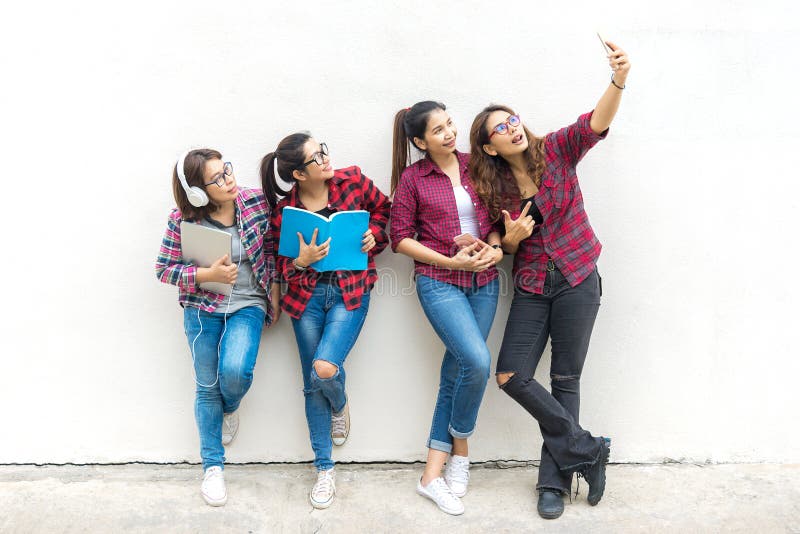 La mujer asiática del grupo que coloca y que sostiene un libro, toma una foto en fondo del blanco de la pared fotografía de archivo La mujer asiática del grupo que coloca y que sostiene un libro, toma una foto en fondo del blanco de la pared fotografía de archivo