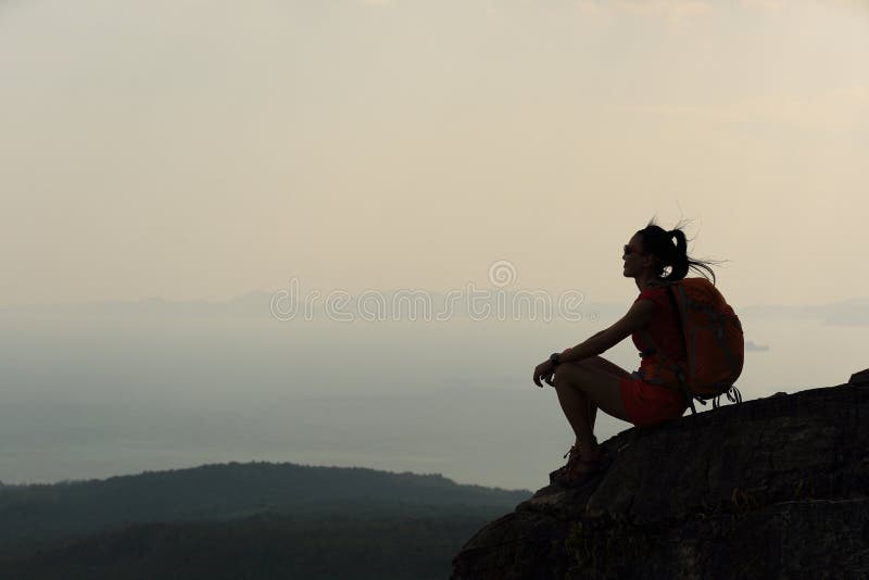 La mujer asiática disfruta de la visión en el pico de montaña de la puesta del sol foto de archivo La mujer asiática disfruta de la visión en el pico de montaña de la puesta del sol foto de archivo