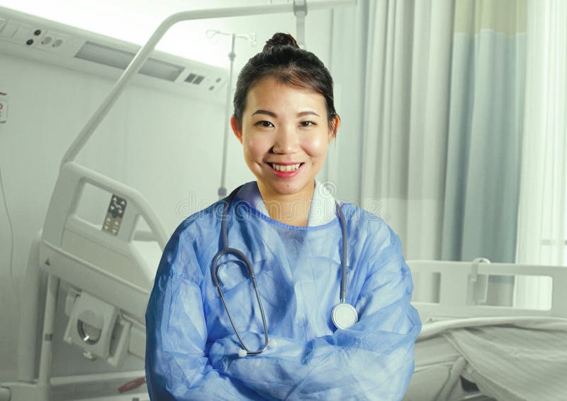 La mujer asiática feliz y atractiva joven del doctor de la medicina china en azul friega la sonrisa alegre en la cama del sitio d imagen de archivo La mujer asiática feliz y atractiva joven del doctor de la medicina china en azul friega la sonrisa alegre en la cama del sitio d imagen de archivo