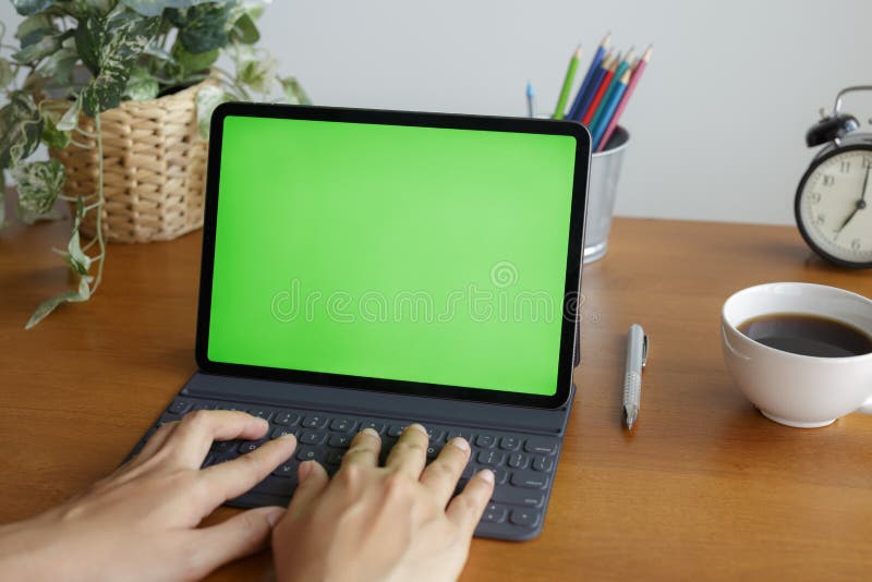 La mujer asiática que las manos están utilizando la tableta tiene pantalla verde en el escritorio al lado de la ventana fotos de archivo La mujer asiática que las manos están utilizando la tableta tiene pantalla verde en el escritorio al lado de la ventana fotos de archivo