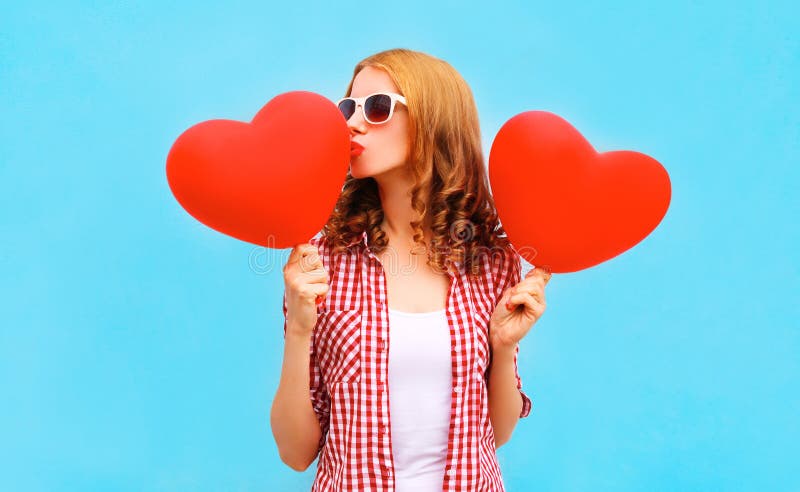 La mujer bonita besa un balón de aire rojo en la forma de un corazón imagen de archivo La mujer bonita besa un balón de aire rojo en la forma de un corazón imagen de archivo