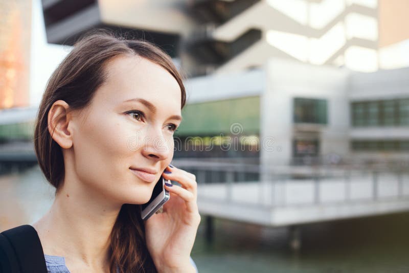 La mujer caucásica hermosa joven en ropa del estilo sport está hablando en su teléfono móvil que se coloca cerca de los edificios imagen de archivo La mujer caucásica hermosa joven en ropa del estilo sport está hablando en su teléfono móvil que se coloca cerca de los edificios imagen de archivo
