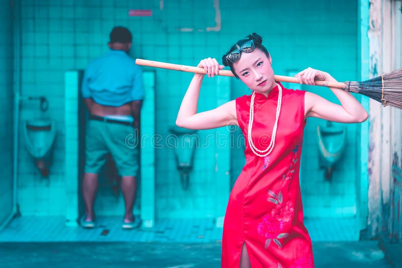 La mujer china está consiguiendo lista para limpiar el retrete sucio masculino fotos de archivo La mujer china está consiguiendo lista para limpiar el retrete sucio masculino fotos de archivo