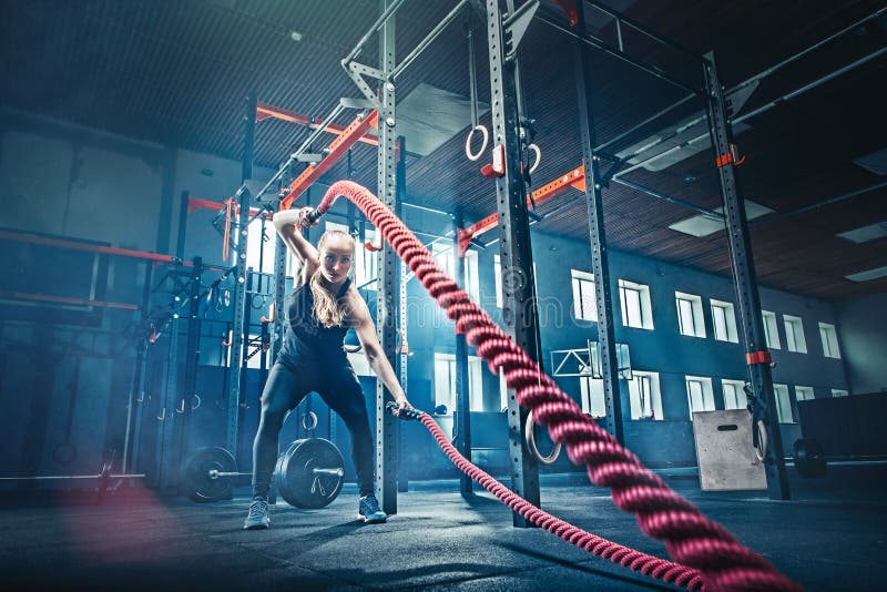 La mujer con batalla de la cuerda de la batalla ropes ejercicio en el gimnasio de la aptitud foto de archivo libre de regalías La mujer con batalla de la cuerda de la batalla ropes ejercicio en el gimnasio de la aptitud foto de archivo libre de regalías