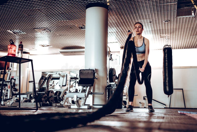 La mujer con batalla de la cuerda de la batalla ropes ejercicio en el gimnasio de la aptitud foto de archivo La mujer con batalla de la cuerda de la batalla ropes ejercicio en el gimnasio de la aptitud foto de archivo