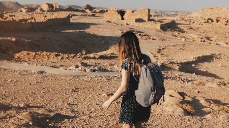 La mujer con la mochila explora ruinas antiguas del desierto El turista europeo hermoso camina en rocas y la arena Masada Israel