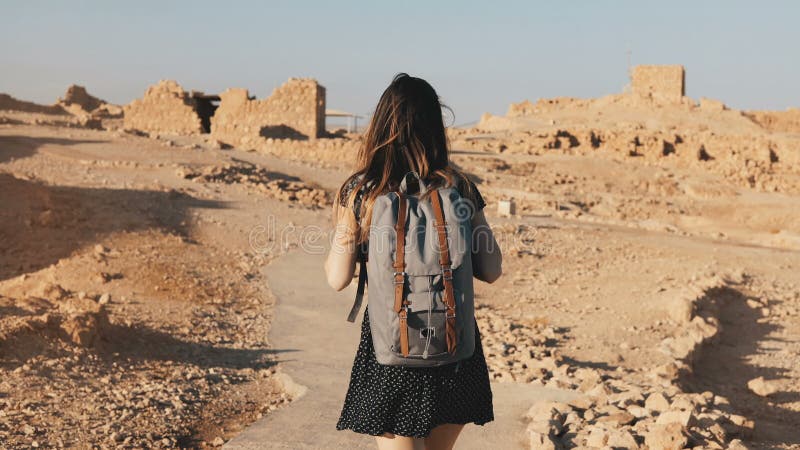 La mujer con la mochila explora ruinas antiguas del desierto El turista europeo hermoso camina en rocas y la arena Masada Israel