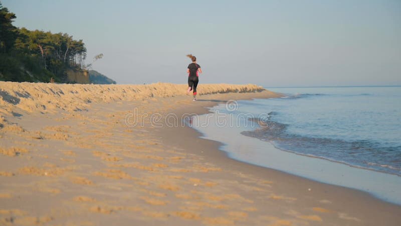 La mujer corre por la playa del mar