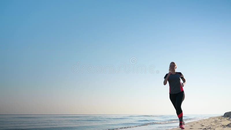 La mujer corre por la playa del mar