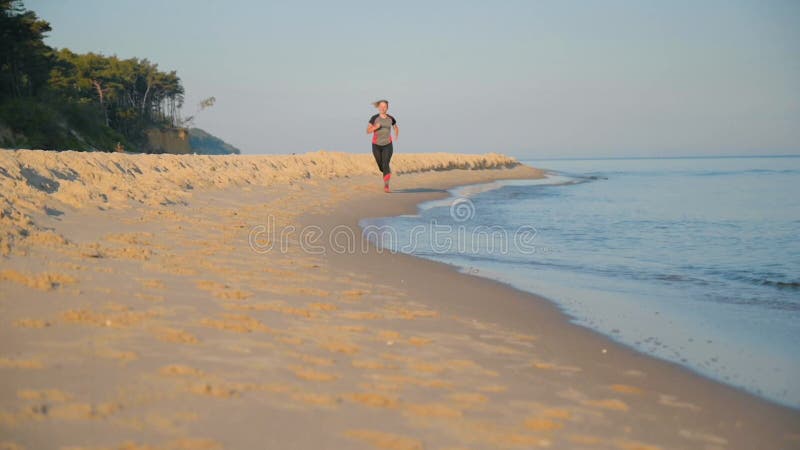 La mujer corre por la playa del mar