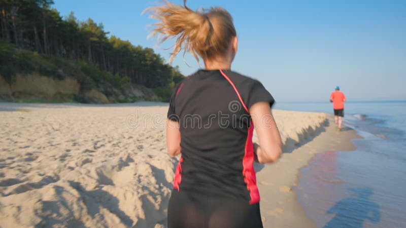 La mujer corre por la playa del mar