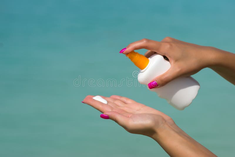La mujer da poner la protección solar de una botella del suncream fotografía de archivo libre de regalías La mujer da poner la protección solar de una botella del suncream fotografía de archivo libre de regalías