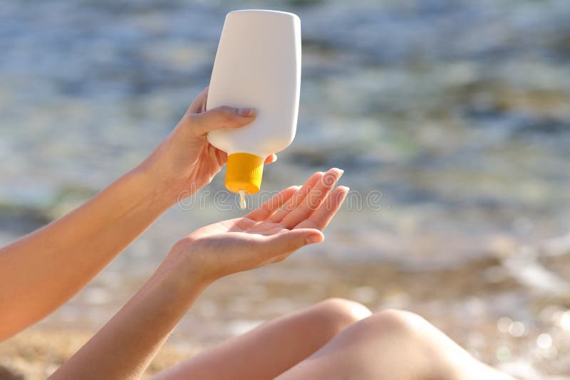 La mujer da poner la protección solar de una botella en la playa imágenes de archivo libres de regalías La mujer da poner la protección solar de una botella en la playa imágenes de archivo libres de regalías
