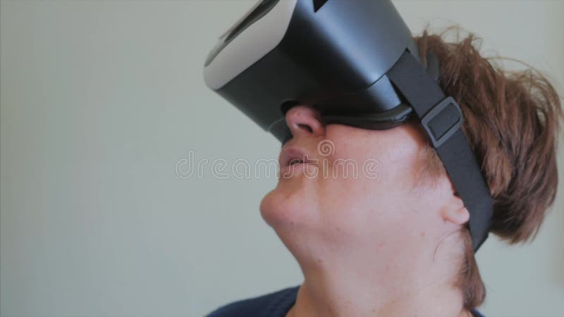 La mujer de mediana edad utiliza los vidrios de una realidad virtual en casa metrajes