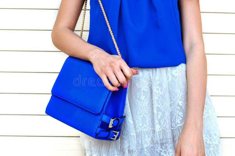 La mujer de moda en blusa azul y el cordón blanco bordean sostener el pequeño bolso de cuero azul w fotografía de archivo La mujer de moda en blusa azul y el cordón blanco bordean sostener el pequeño bolso de cuero azul w fotografía de archivo