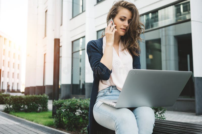 La mujer de negocios bonita joven se sienta en distrito financiero y la discusión sobre trabajo en la información del smartphone foto de archivo La mujer de negocios bonita joven se sienta en distrito financiero y la discusión sobre trabajo en la información del smartphone foto de archivo