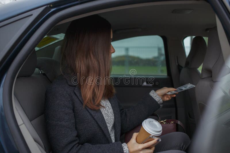 La mujer de negocios que paga con el conductor y alista para dejar el coche imágenes de archivo libres de regalías La mujer de negocios que paga con el conductor y alista para dejar el coche imágenes de archivo libres de regalías