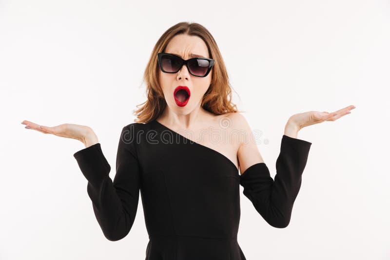 La mujer elegante confusa en vestido y gafas de sol encoge sus hombros fotografía de archivo libre de regalías La mujer elegante confusa en vestido y gafas de sol encoge sus hombros fotografía de archivo libre de regalías