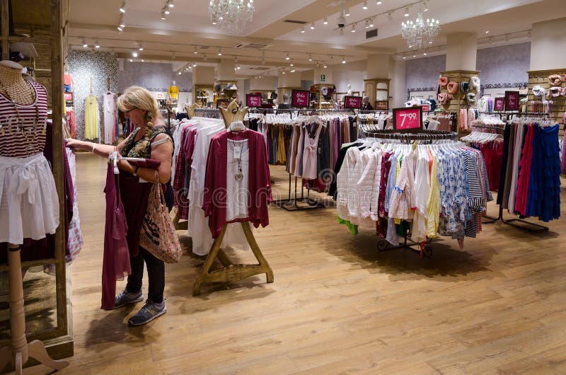 La mujer elige la ropa en la tienda de la ropa de las mujeres, Barcelona, España fotos de archivo libres de regalías La mujer elige la ropa en la tienda de la ropa de las mujeres, Barcelona, España fotos de archivo libres de regalías