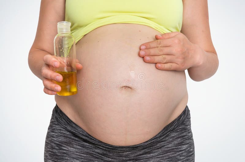 La mujer embarazada está aplicando la grasa natural de la piel hidratante en el vientre fotos de archivo La mujer embarazada está aplicando la grasa natural de la piel hidratante en el vientre fotos de archivo