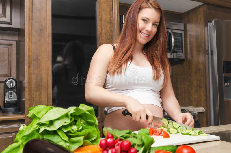 La mujer embarazada hace una ensalada foto de archivo La mujer embarazada hace una ensalada foto de archivo