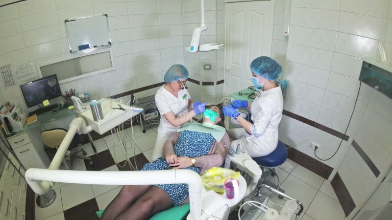 La mujer en la clínica del dentista consigue el tratamiento dental para llenar una cavidad en un diente Restauración dental y mat metrajes