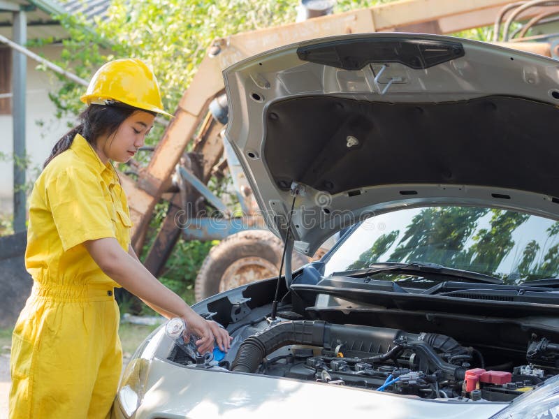 La mujer en el técnico de ropa de trabajo está abriendo la tapa del tanque del motor y rellenando el nivel del agua foto de archivo La mujer en el técnico de ropa de trabajo está abriendo la tapa del tanque del motor y rellenando el nivel del agua foto de archivo