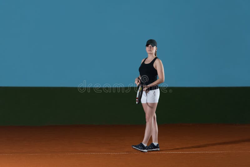 La mujer en ropa de deportes sirve la pelota de tenis fotografía de archivo La mujer en ropa de deportes sirve la pelota de tenis fotografía de archivo