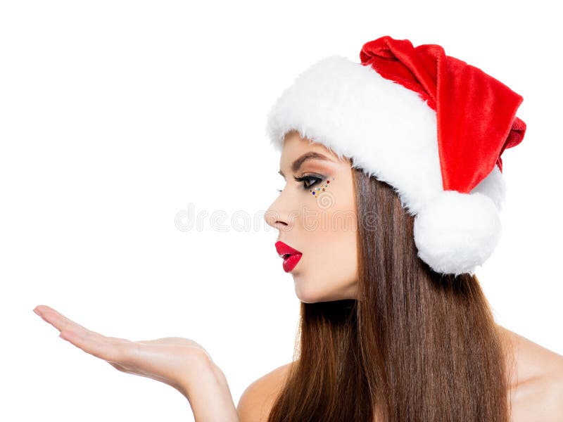 La mujer en un sombrero de santa envía un beso La cara de la mujer hermosa con las palmas cerca de la cara con la muestra que se imagen de archivo