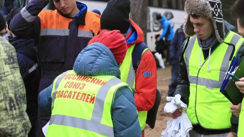 La mujer en uniforme del rescate distribuye las camisas a los salvadores jovenes en la calle enseñanza