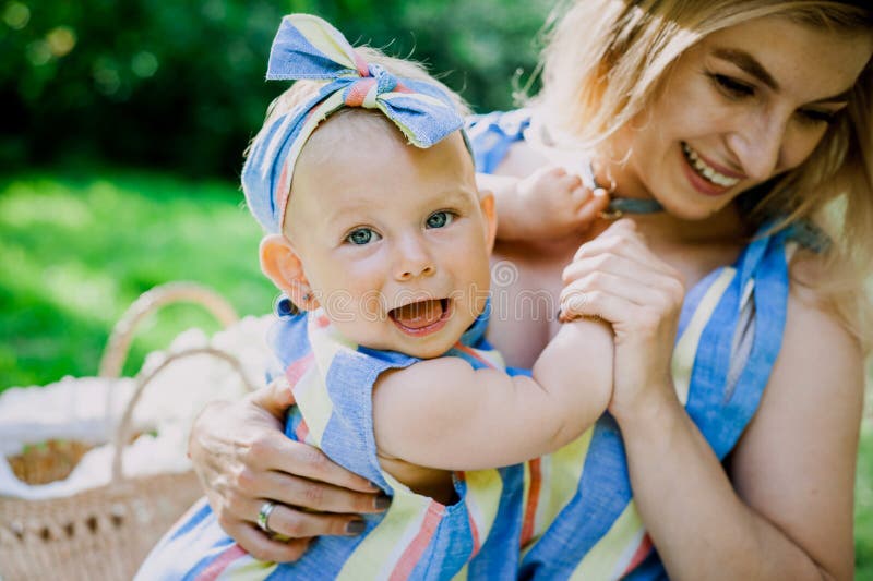 La mujer en vestido azul cría para arriba a su pequeña hija en la misma ropa foto de archivo libre de regalías La mujer en vestido azul cría para arriba a su pequeña hija en la misma ropa foto de archivo libre de regalías