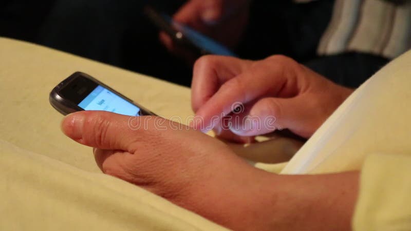 La mujer envejecida centro utiliza smartphone mientras que se sienta en el sofá almacen de metraje de vídeo