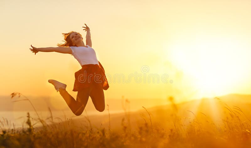 La mujer feliz salta, disfruta, en puesta del sol en naturaleza imágenes de archivo libres de regalías