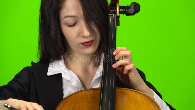 La mujer fija el violoncelo con sus fingeres Pantalla verde Cierre para arriba