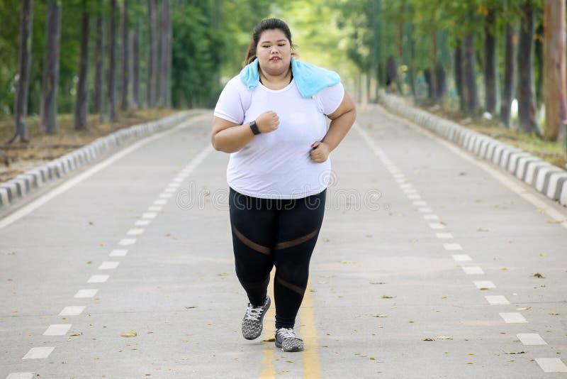 La mujer gorda que hace funcionamientos ejercita en el camino imagen de archivo La mujer gorda que hace funcionamientos ejercita en el camino imagen de archivo