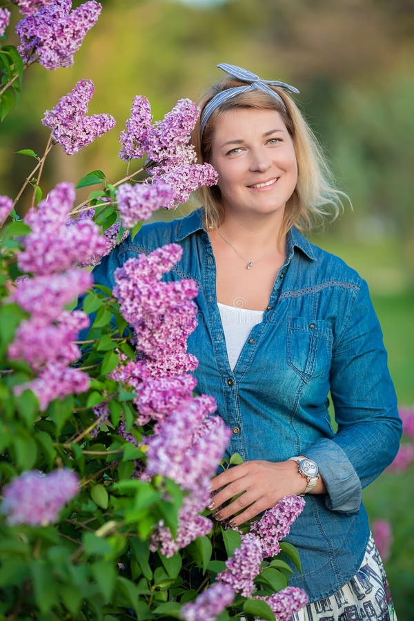 La mujer hermosa con el manojo de la lila y la guirnalda de flores en primavera cultivan un huerto, retrato de la madre embarazad imagenes de archivo La mujer hermosa con el manojo de la lila y la guirnalda de flores en primavera cultivan un huerto, retrato de la madre embarazad imagenes de archivo