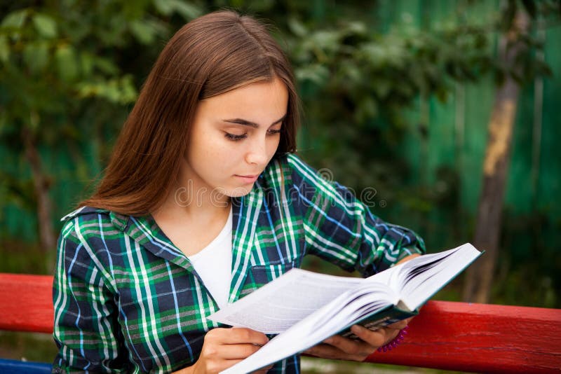 La mujer hermosa con el pelo largo es libro de lectura al aire libre foto de archivo libre de regalías La mujer hermosa con el pelo largo es libro de lectura al aire libre foto de archivo libre de regalías