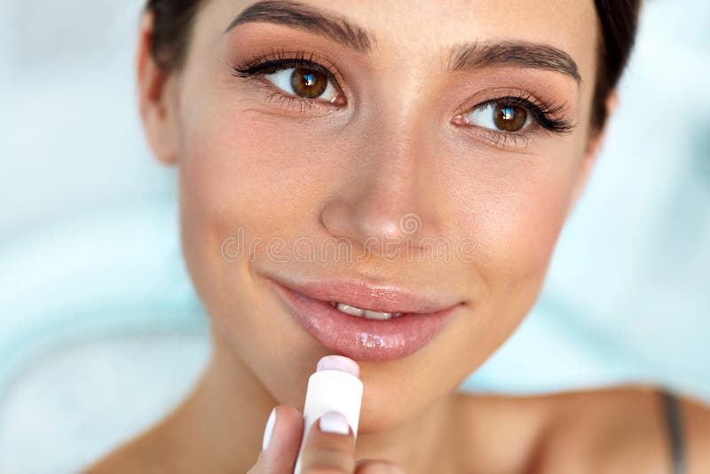 La mujer hermosa con la cara de la belleza aplica bálsamo en los labios Cuidado de piel imagen de archivo La mujer hermosa con la cara de la belleza aplica bálsamo en los labios Cuidado de piel imagen de archivo