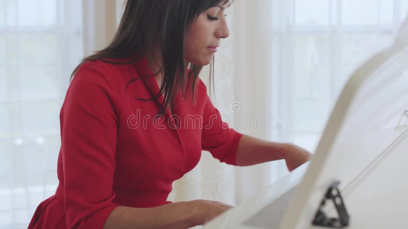 La mujer hermosa da a juegos un piano blanco