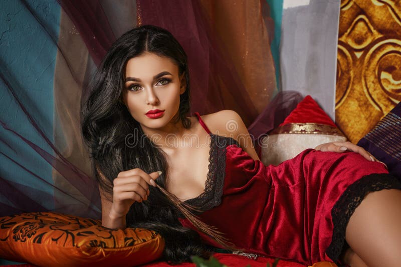 La mujer hermosa de moda miente en una bata de casa roja foto de archivo libre de regalías La mujer hermosa de moda miente en una bata de casa roja foto de archivo libre de regalías