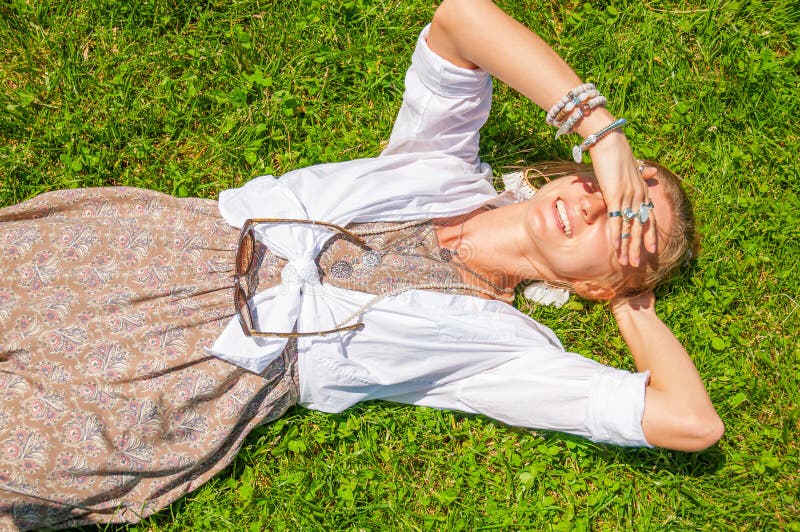 La mujer hermosa del estilo del boho con muchos accesorios est? mintiendo en hierba verde Mometn feliz imágenes de archivo libres de regalías La mujer hermosa del estilo del boho con muchos accesorios est? mintiendo en hierba verde Mometn feliz imágenes de archivo libres de regalías