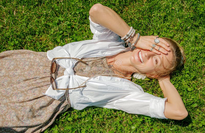 La mujer hermosa del estilo del boho con muchos accesorios est? mintiendo en hierba verde Mometn feliz imágenes de archivo libres de regalías La mujer hermosa del estilo del boho con muchos accesorios est? mintiendo en hierba verde Mometn feliz imágenes de archivo libres de regalías