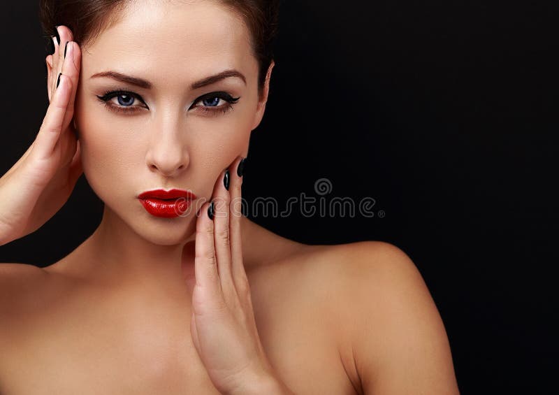 Beautiful makeup woman with red lips posing with hands near health skin face on black background with empty copy space. Beautiful makeup woman with red lips posing with hands near health skin face on black background with empty copy space