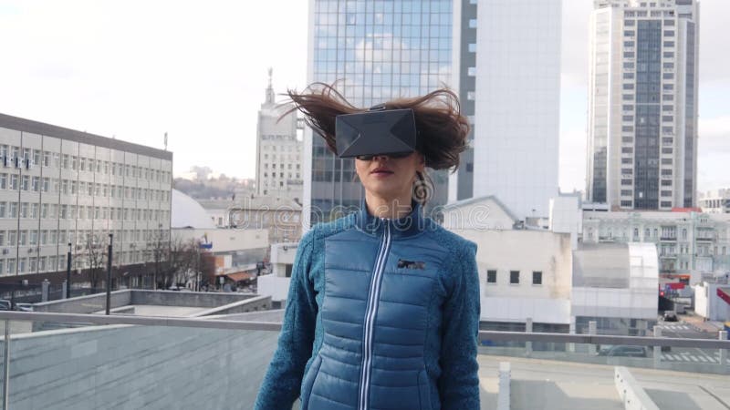 La mujer hermosa joven hace deporte del ejercicio de la aptitud con las auriculares de la realidad virtual