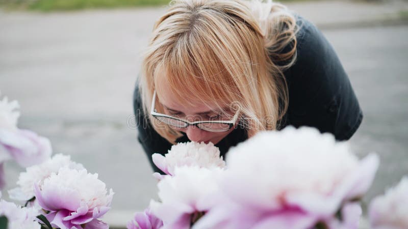 La mujer huele las flores en el parque