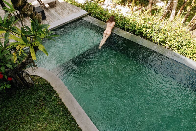 La mujer irreconocible en el bikini beige que se relaja en piscina del infinito en Bali admira una hermosa vista de las palmeras fotos de archivo La mujer irreconocible en el bikini beige que se relaja en piscina del infinito en Bali admira una hermosa vista de las palmeras fotos de archivo